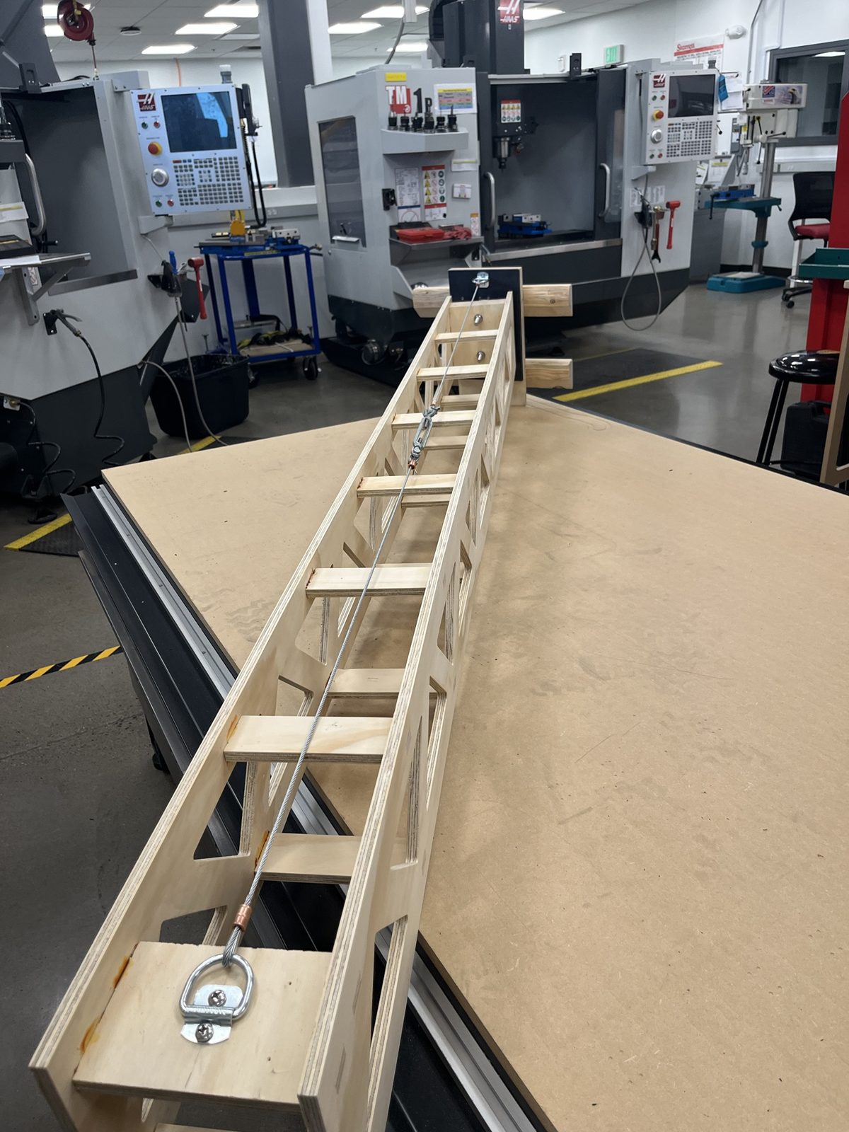 The assembled truss arm lying on the router table with its cable and turnbuckle installed