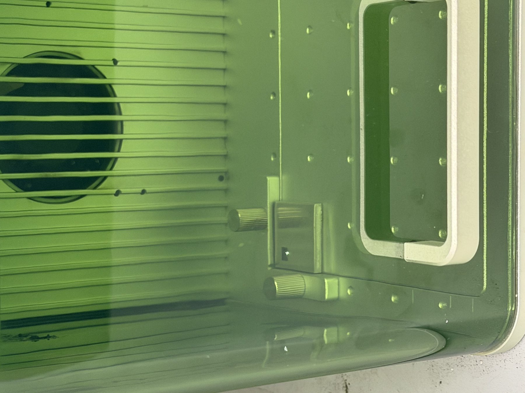 Laser engraving a test pattern, seen through the green safety window of the xTool F1